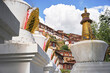 From below of vibrant blue sky with clouds over small red houses and golden monuments on pedestals