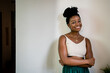 © Rafa Cortes/ADDICTIVE STOCK - Cheerful African American female in white top and round transparent eyeglasses with dark hair tied up looking at camera while standing in room near grey wall