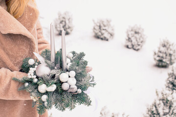 Advent new year decoration with two silver candles and fir branches decorated with white glass balls and snow. Christmas background