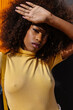 © Victor Torres/ADDICTIVE STOCK - Portrait of a curly haired black woman looking at camera in front of a yellow background