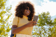 © Victor Torres/ADDICTIVE STOCK - Black woman with afro hair listening to music on mobile with a backpack on her back