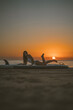 © Alvaro Montero/ADDICTIVE STOCK - Side view of fit female in swimsuit lying on paddleboard on sandy coast and looking at camera on background of sunset sky