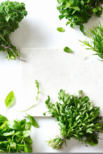 Flat Lay With Various Herbs And Lettuce And Marble Cutting Board On White Background