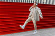 © David Munoz/ADDICTIVE STOCK - Full body joyful laughing Asian male in casual wear listening to favorite song in wireless headphones while walking along red metal fence
