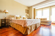 © Javier De La Torre/ADDICTIVE STOCK - Cozy spacious bed with cushions and coverlets in room with wooden parquet and panoramic windows