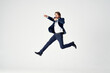 © SHOTPRIME STUDIO - Energetic business man in a blue suit jumps up on a light background success joy emotions