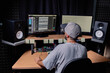 © Jose Carlos Gutierrez/ADDICTIVE STOCK - Back view of unrecognizable male musician sitting at table with monitors and stereo speakers while recording audio in studio