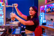 © Javier De La Torre/ADDICTIVE STOCK - Side view of happy young female barkeeper pouring beer into glass while working in bar looking at camera