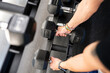 © Jose Carlos Cerdeno/ADDICTIVE STOCK - Anonymous person with smart watch taking heavy dumbbells from rack during weightlifting workout in gym