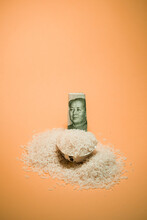 High Angle Of Pile Of Rice In Bowl With Chinese Renminbi Bill Arranged On Peach Background In Studio