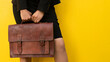 © Jose Carlos Cerdeno/ADDICTIVE STOCK - Crop anonymous female in skirt with stylish brown leather handbag standing against yellow background