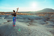 © Miguel Cano/ADDICTIVE STOCK - Side view of unrecognizable female in sportswear standing with outstretched arms on rocky hill among desert badlands against blue cloudy sky