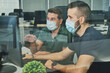 © Philippe Degroote/ADDICTIVE STOCK - Male coworkers in medical masks sitting together using program for software during coronavirus pandemic