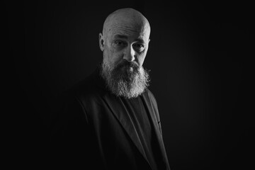 Wall Mural - close up photo, portrait of a serious, thoughtful, bearded man on a dark background confident and dramatic looking straight. Concept of male portrait. Black and white photo. Low key