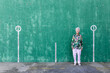 © Sergio Victor Vega/ADDICTIVE STOCK - Full body of elegant elderly female in stylish outfit standing against green wall with numbers on parking lot