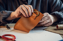 A Young Shoemaker Manually Sews Decorative Elements To Leather Shoes In The Workshop.