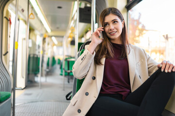 female passenger sits on the tram and talks to the phone. pretty caucasian woman riding in public tr