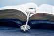 the key lies on an open bible book. metaphor for discovering wisdom through the study of religious literature
