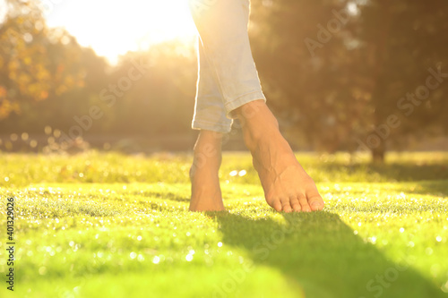 Young woman walking barefoot on fresh green grass, closeup Fotobehang