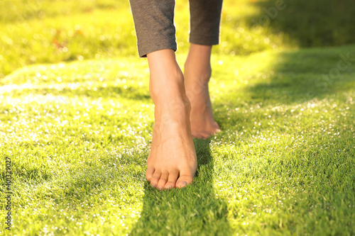 Young woman walking barefoot on fresh green grass, closeup Canvas
