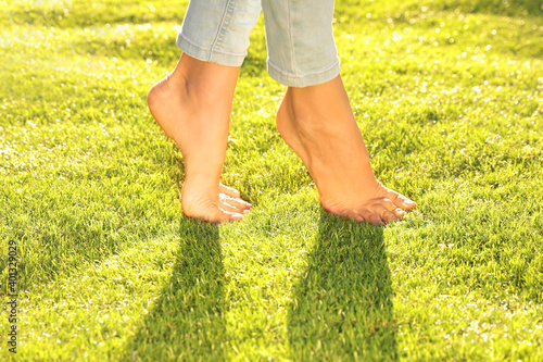 Foto Young woman walking barefoot on fresh green grass, closeup