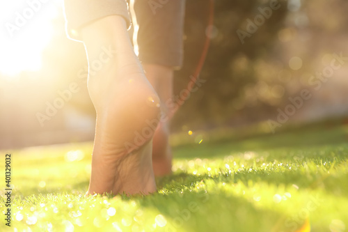 Young woman walking barefoot on fresh green grass, closeup Fotobehang