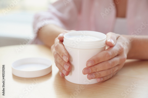 Woman with jar of moisturizing cream at table, closeup Billede på lærred