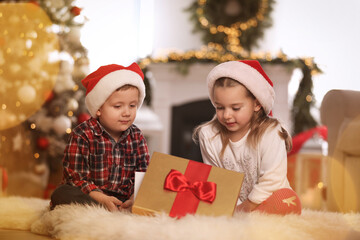 Wall Mural - Cute children opening gift box in room decorated for Christmas