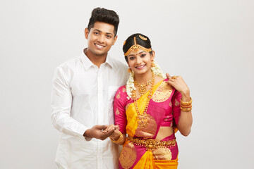 Attractive happy south Indian couple in traditional dress on white.