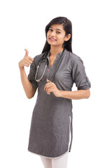 Wall Mural - Attractive smiling young Indian female doctor showing hand sign on white.