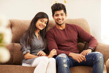 Wall Mural - Young beautiful couple chatting on sofa at home