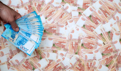 A man's hand holds Russian money worth two thousand rubles in close-up against the background of five thousand bills. The concept of Finance.