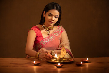 Poster - Beautiful Hindu Indian young women lightening Diya on Diwali day.