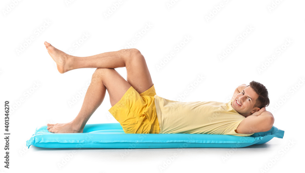 Young man lying on inflatable mattress against white background