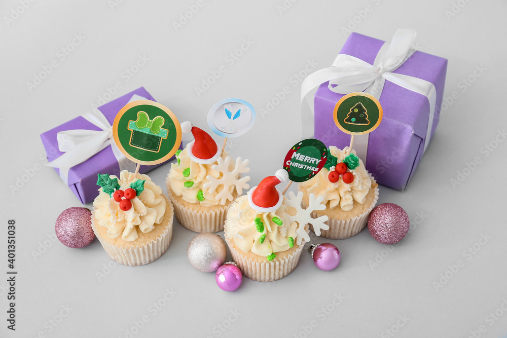 Tasty Christmas cupcakes on light background