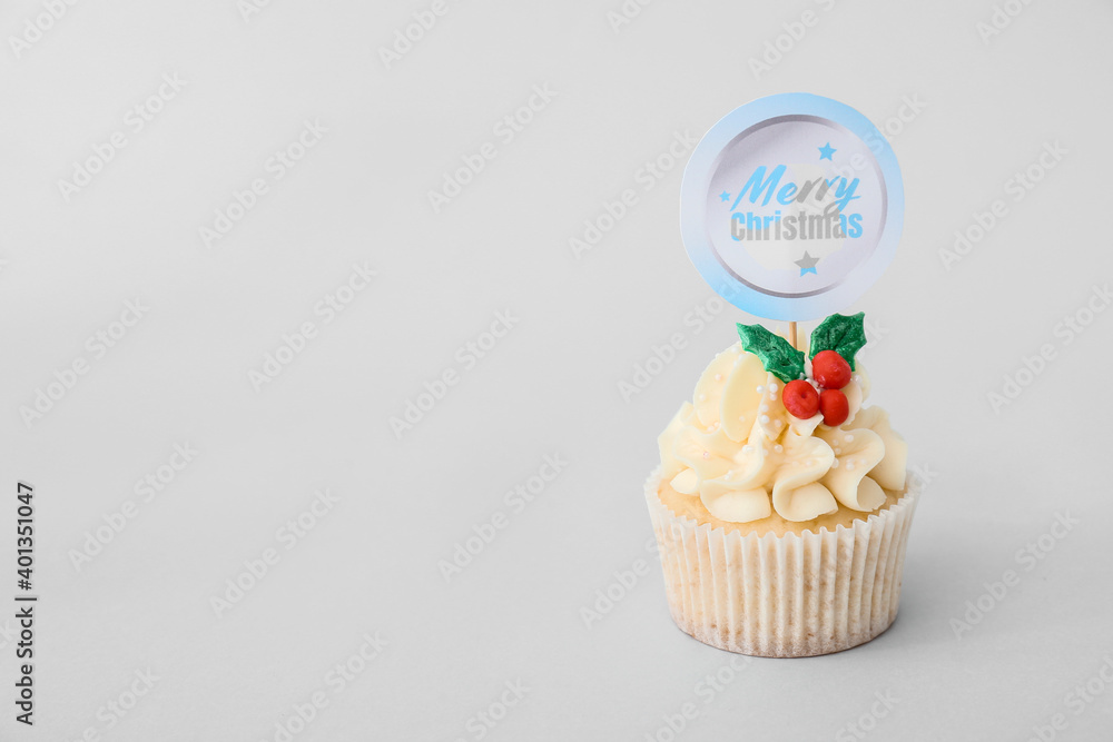 Tasty Christmas cupcake on light background