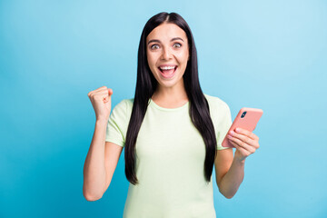 Wall Mural - Photo portrait of happy celebrating woman holding phone in one hand isolated on pastel blue colored background