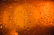 Water drops on a window with orange background on a rainy day.