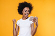 © Drobot Dean - Happy young african american woman rejoicing while holding cellphone
