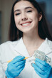 © DmitryStock - Portrait of a pretty brunette in whose hands a model of teeth and a special tool