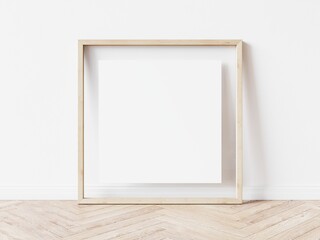 Empty square picture frame with light wood border standing on wooden floor leaning on white wall. 3D Illustration.