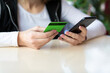 © junky_jess - Female hands with green credit card and smartphone, close up. Customer payment for service via the internet, selective focus.