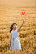 © Blue Jean Images - Little girl playing with paper windmill in wheat field