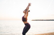 © BullRun - Caucasian female yogi doing Chair Pose during morning training at seashore beach with sunrise, experienced woman in tracksuit inspired with workout concentration for seeking chakra enlightenment