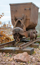 Old Rusty Mining Cart On A Rail Track . Decoration In The Park.