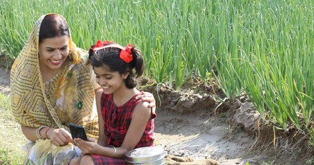 Wall Mural - Rural mother and daughter using mobile phone on agriculture field