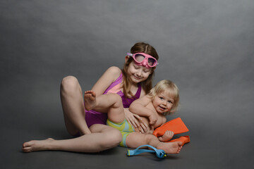 two children in swimming trunks, swimming masks and fins are having fun.