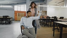 Female Pushing Chair With Her Colleague, Team Of Diverse Employees Celebrating Success Arranging Chair Racing In Office