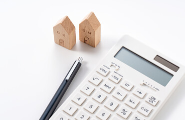 a model of a house, a calculator and a pen on a white background