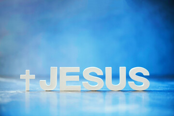 Name JESUS made with cement letters on blue light marble background. Copy space. Biblical, spiritual or christian reminder